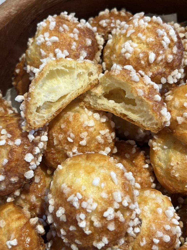 coupe d'une chouquette maison cuite, dans un saladier avec d'autres chouquettes entières