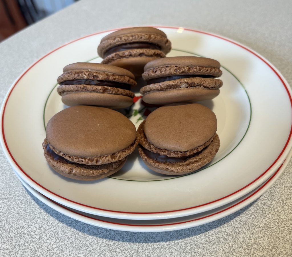 macarons au chocolat lisses sur deux assiettes a dessert
